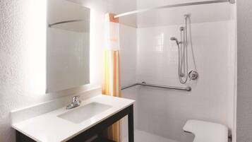 A bathroom with a white sink, a mirror, a shower with a grab bar, and a white toilet.