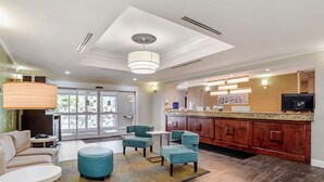 A hotel lobby with a reception desk, seating area, and a large window. - Sleep Inn & Suites Montgomery East I-85 (Montgomery)