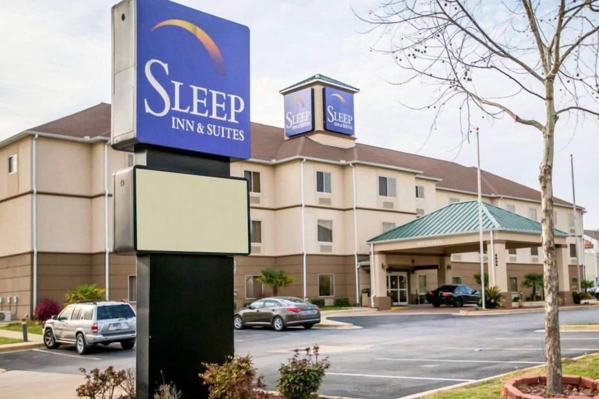 A Sleep Inn & Suites building with a large sign, a covered entrance, and a parking lot.