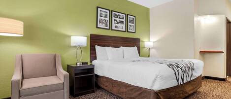 Une chambre d’hôtel comprenant un lit, une chaise, une table de chevet et des lampes fixées au mur.