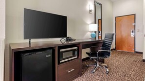 A hotel room with a flat-screen TV, a mini-fridge, a microwave, a desk with a chair, a lamp, and a door. - Sleep Inn & Suites Montgomery East I-85 (Montgomery)