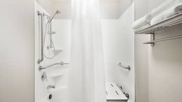 A modern bathroom with a bathtub, shower, and handrails.