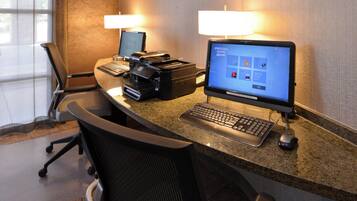 A hotel reception desk with two computers, a printer, and a keyboard.