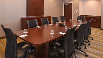 A conference room with a long table, black chairs, and a wooden cabinet.