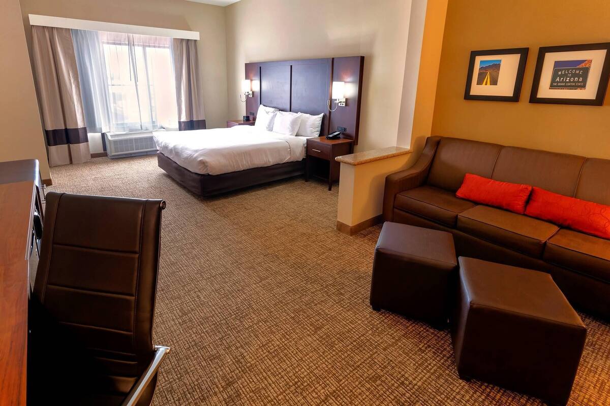 Ein Hotelzimmer mit Bett, Sofa, Schreibtisch und Fernseher.