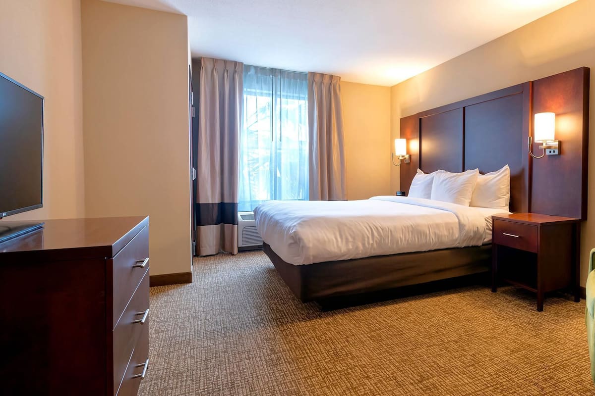 Ein Hotelzimmer mit Bett, Schreibtisch, Stuhl und Fernseher.