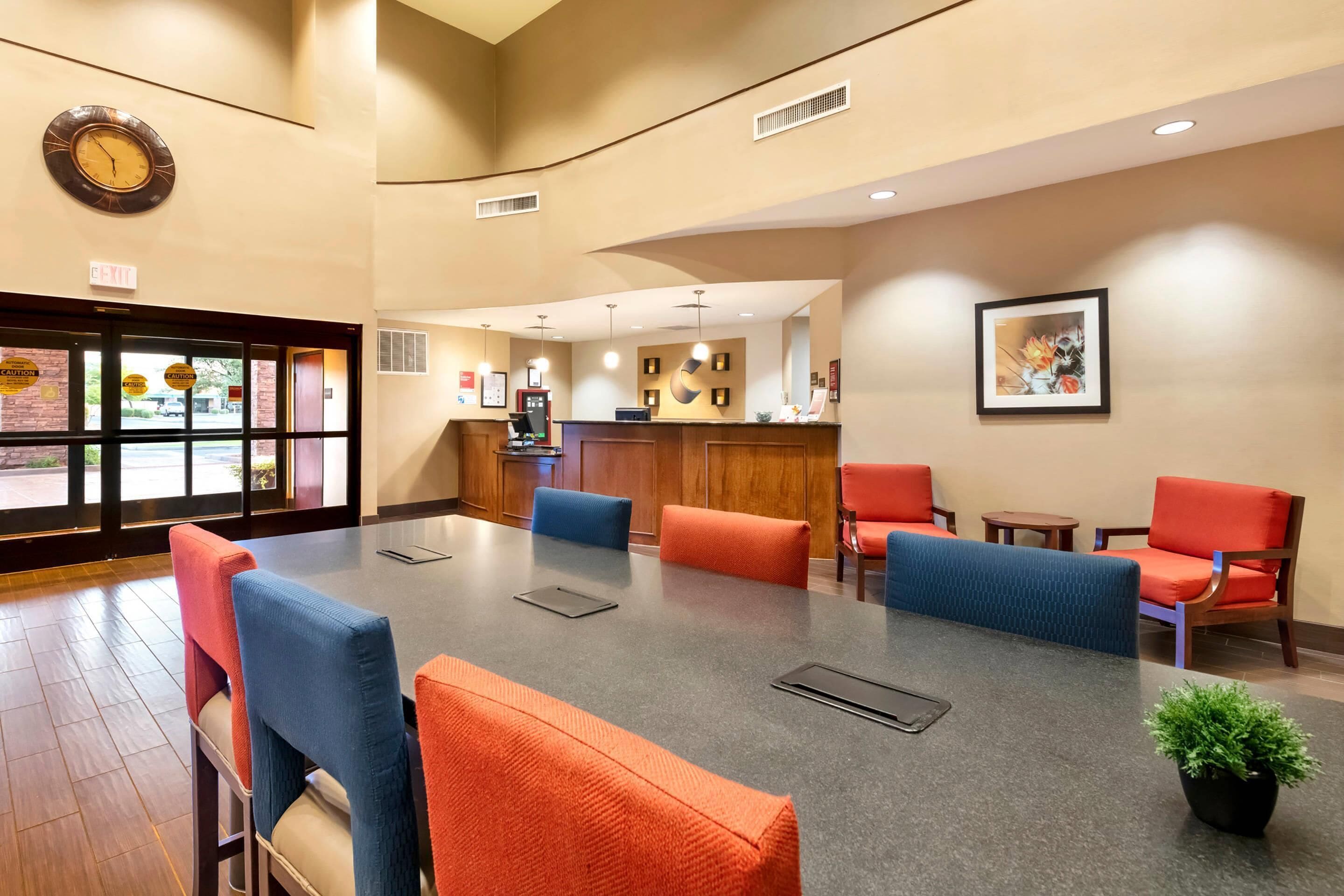Un'hall dell'hotel con reception, area salotto e orologio a parete.