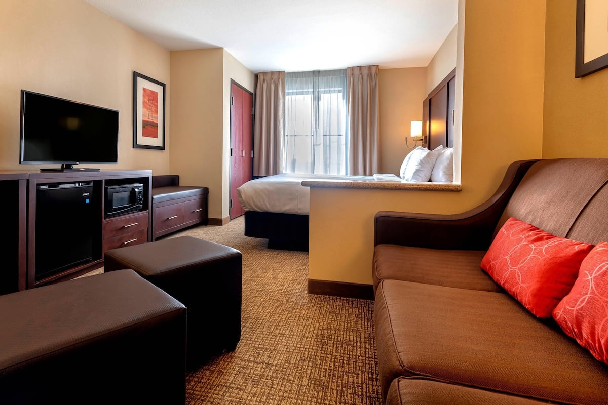 Ein Hotelzimmer mit Fernseher, Bett, Schreibtisch und einer Sitzecke.
