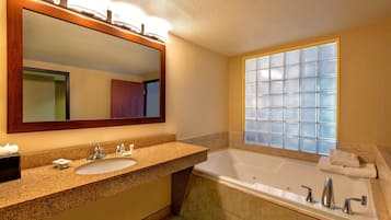 Un baño con un espejo grande, un lavabo, una bañera y una ventana con diseño de cuadrícula.