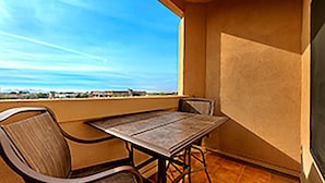 Un balcon avec une table et des chaises, une vue sur le ciel et un sol carrelé.