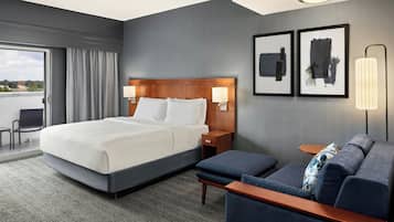 A hotel room with a large bed, a sofa, a small table, and two wall-mounted lamps.