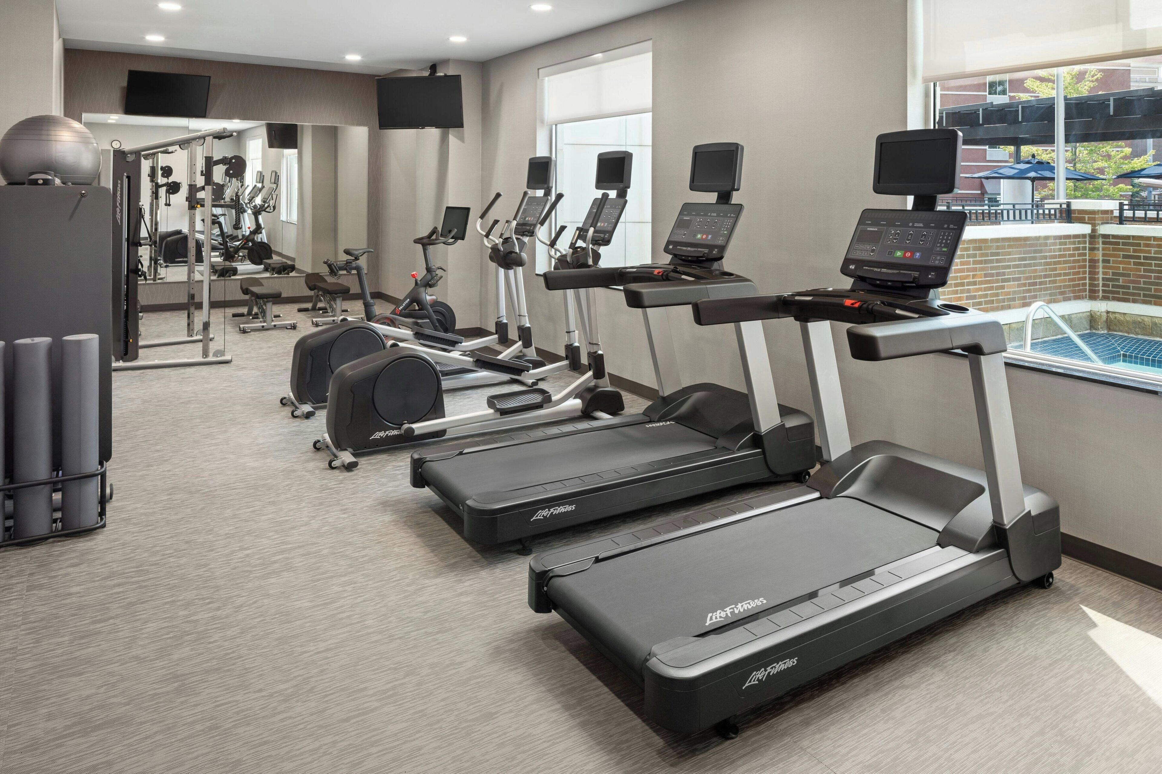 A gym with treadmills, weight machines, and a mirrored wall.