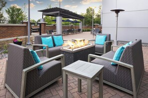 Un espace extérieur aménagé en terrasse, avec des meubles en osier, un foyer et des parasols.