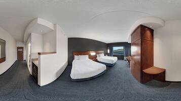 A modern hotel room with a curved ceiling, two beds, a desk, and a wardrobe.