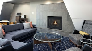 Una sala de estar moderna con chimenea, una mesa de centro de vidrio y un sofá con cojines.