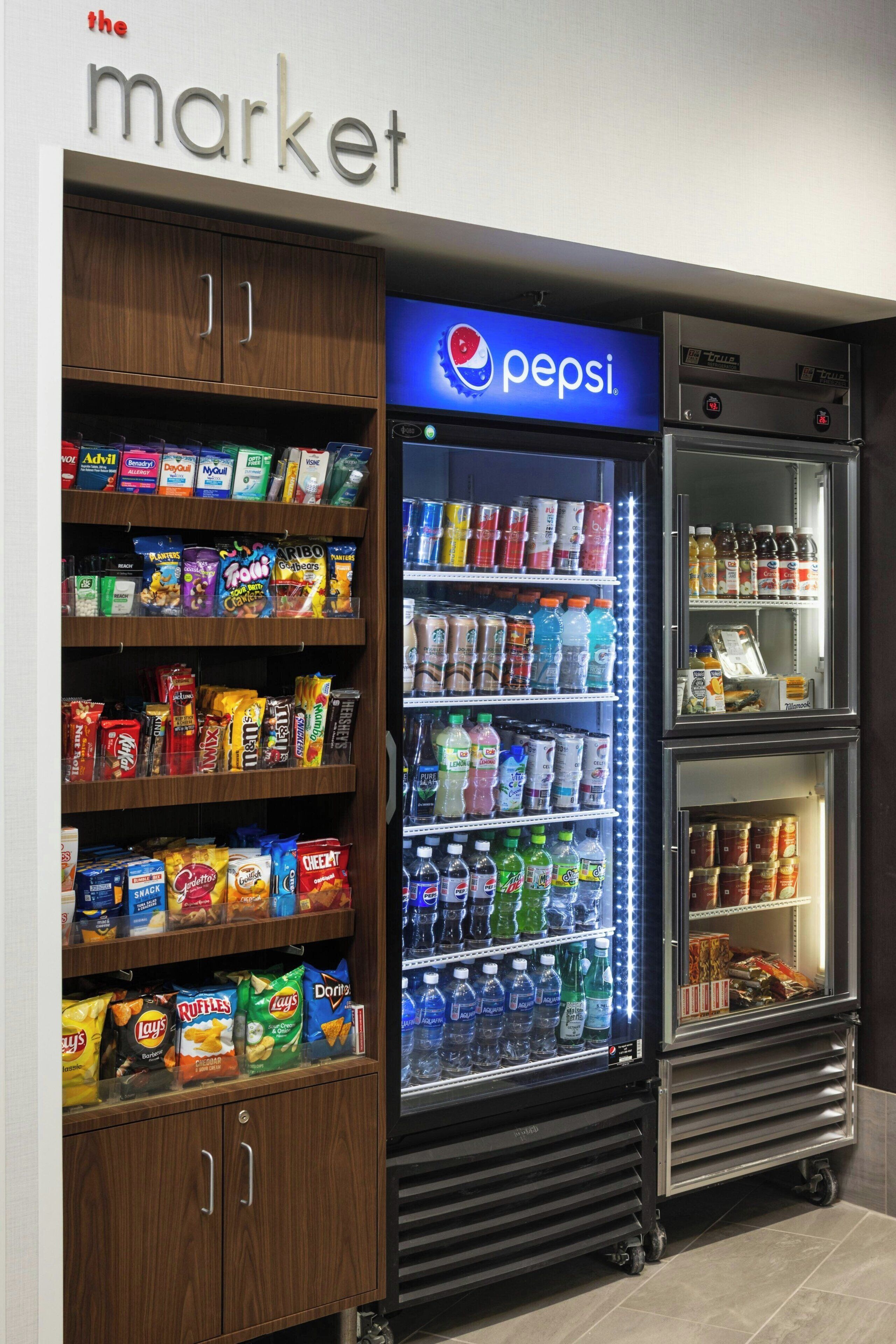 A vending machine stocked with snacks and beverages, including Pepsi, in a store setting.