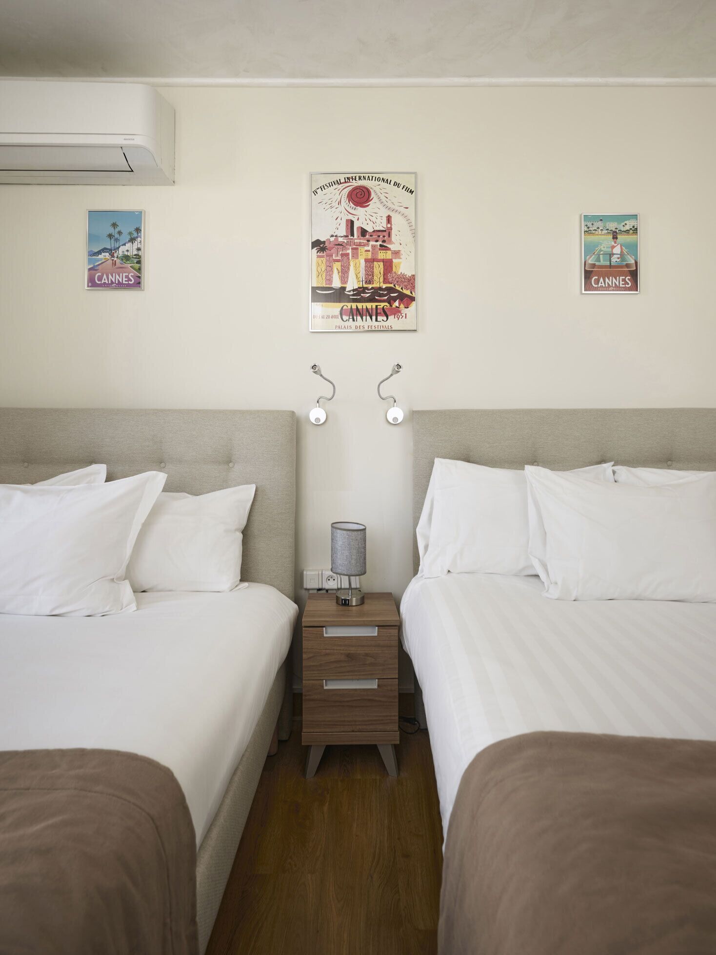 Ein Hotelzimmer mit zwei Betten, einem Nachttisch mit Lampe und Postern an der Wand.