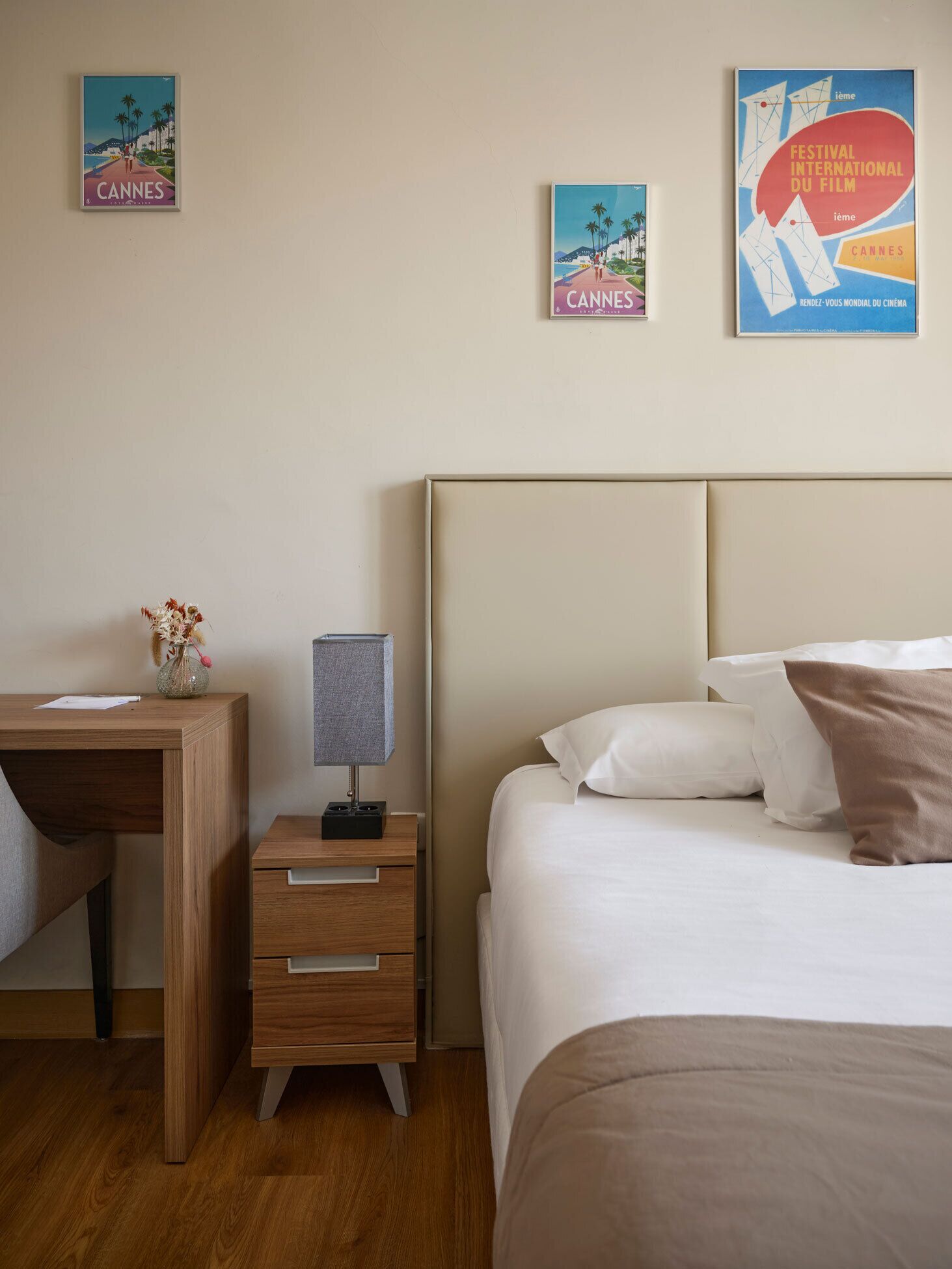 Camera d'albergo con un letto, una scrivania, un comodino e una lampada. Alle pareti sono presenti dei poster.