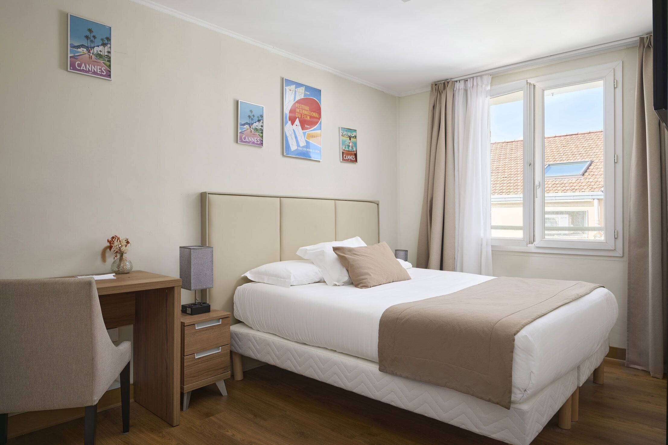 Un dormitorio con cama, escritorio, silla, mesita de noche y ventana con cortinas.