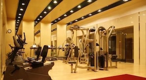 Un gimnasio con diversas máquinas de ejercicio y una alfombra roja.