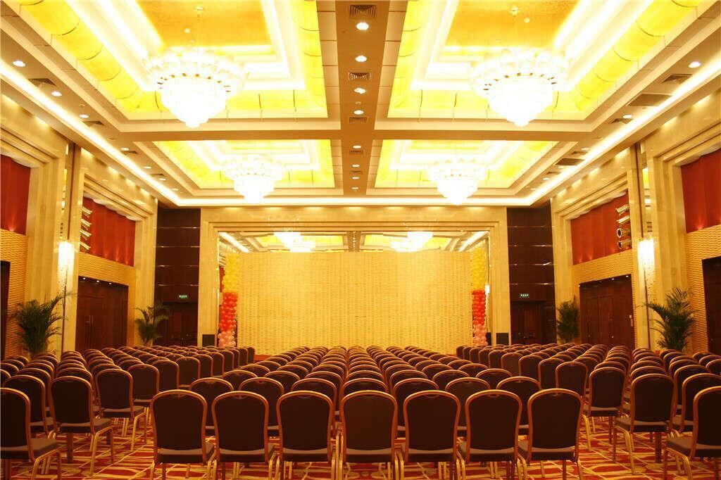 A conference room with rows of chairs, a stage, and chandeliers.