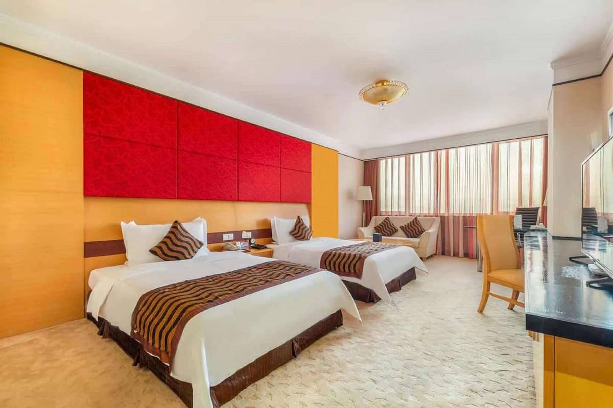 A hotel room with two beds, a desk, and a chair.