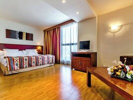 Una habitación de hotel con una cama, televisión, mesa de madera y un armario.