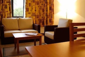 A room with a sofa, a chair, a small table, and a lamp. - Lichinga Hotel by Montebelo (Lichinga)