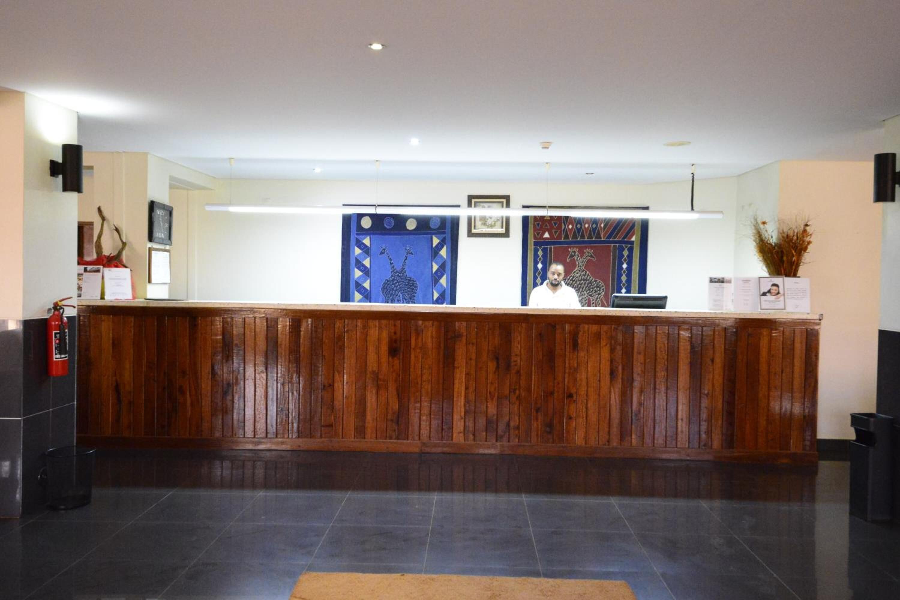 Un mostrador de recepción con detalles de madera, un extintor y cuadros en la pared.