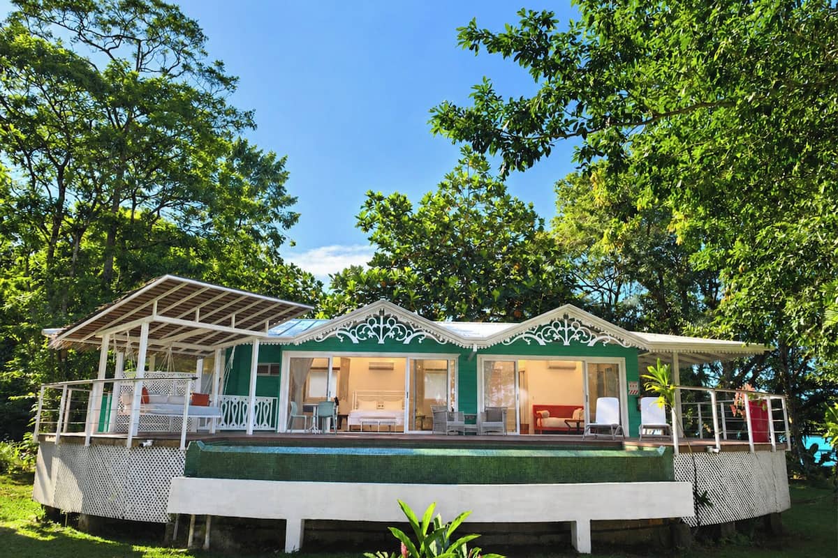 Een tweelaags huis met een overdekte veranda, een zwembad en een tuin.