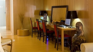 Ein Zimmer mit Holzwandverkleidung, einem Esstisch, Stühlen und zwei Computern.