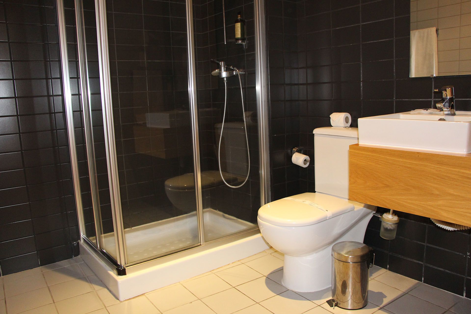 A modern bathroom with a glass-enclosed shower, a white toilet, and a wooden vanity with a sink.