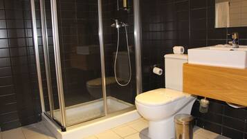 A modern bathroom with a glass-enclosed shower, a white toilet, and a wooden vanity with a sink.