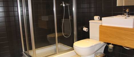 A modern bathroom with a glass-enclosed shower, a white toilet, and a wooden vanity with a sink.