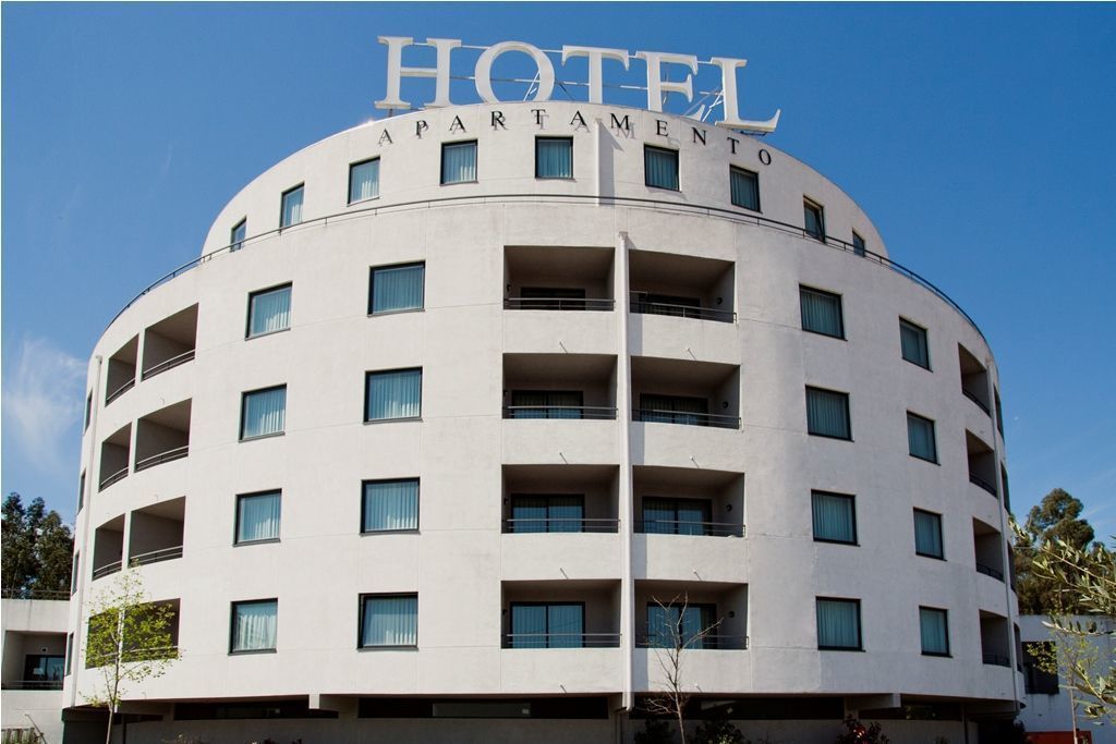 Ein Hotel mit gebogener Fassade, mehreren Balkonen und einem Schild mit der Aufschrift 'HOTEL APARTMENT'.