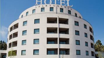 Ein Hotel mit gebogener Fassade, mehreren Balkonen und einem Schild mit der Aufschrift 'HOTEL APARTMENT'.