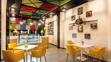A cafe interior with yellow chairs, a coffee bar, and a colorful ceiling.