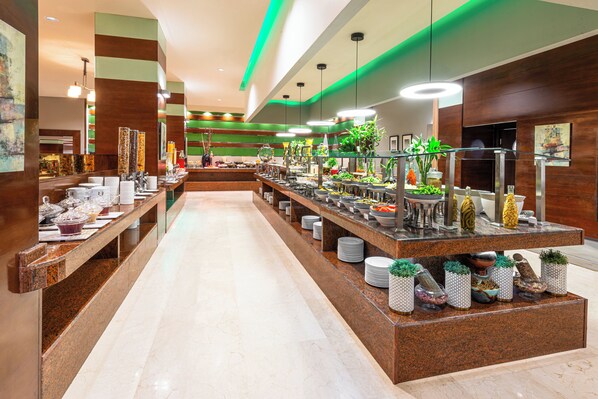 A buffet area with multiple serving stations, a long counter, and a variety of food and drink options. - Holiday Inn Riyadh al qasr by IHG (Riyadh)