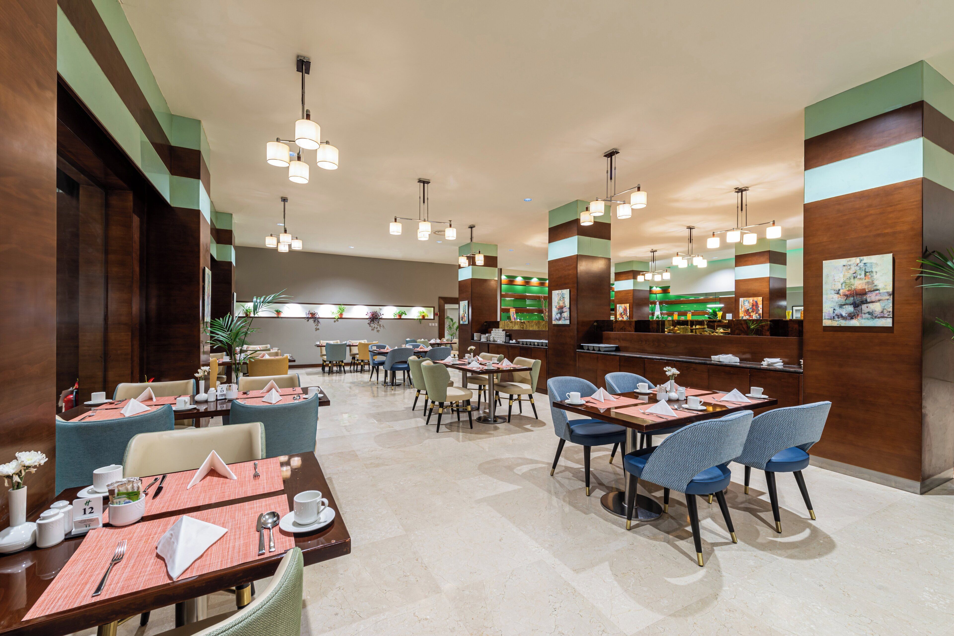 A hotel lobby with multiple dining tables, chairs, and a reception area.