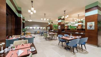 A hotel lobby with multiple dining tables, chairs, and a reception area.
