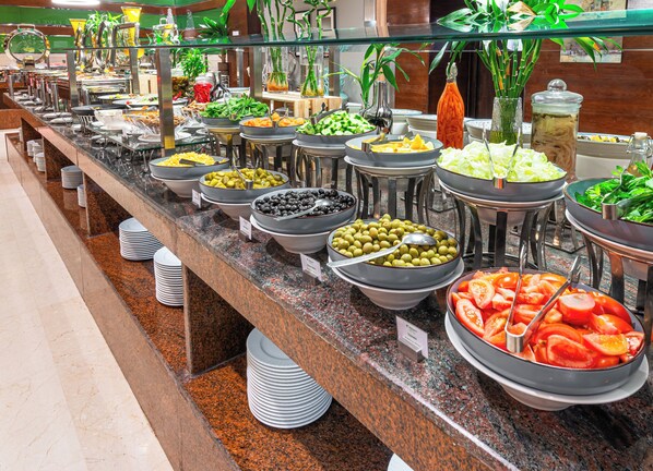 Een buffet met diverse gerechtjes, waaronder olijven, tomaten en salades.