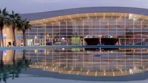 Un edificio moderno con fachada de vidrio y una piscina reflectante al frente.