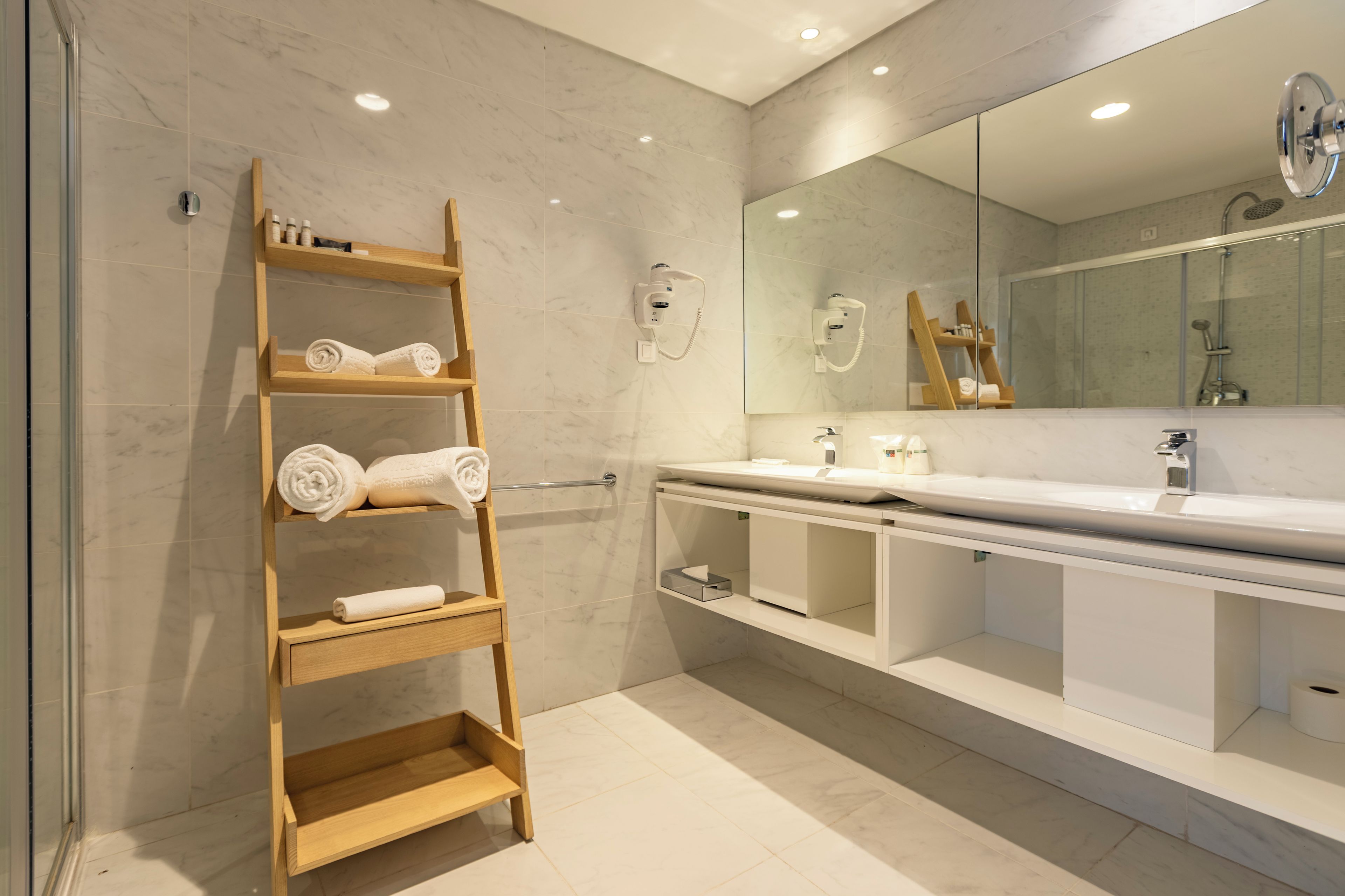 Un baño moderno con un perchero de madera, un espejo grande y una zona de ducha.