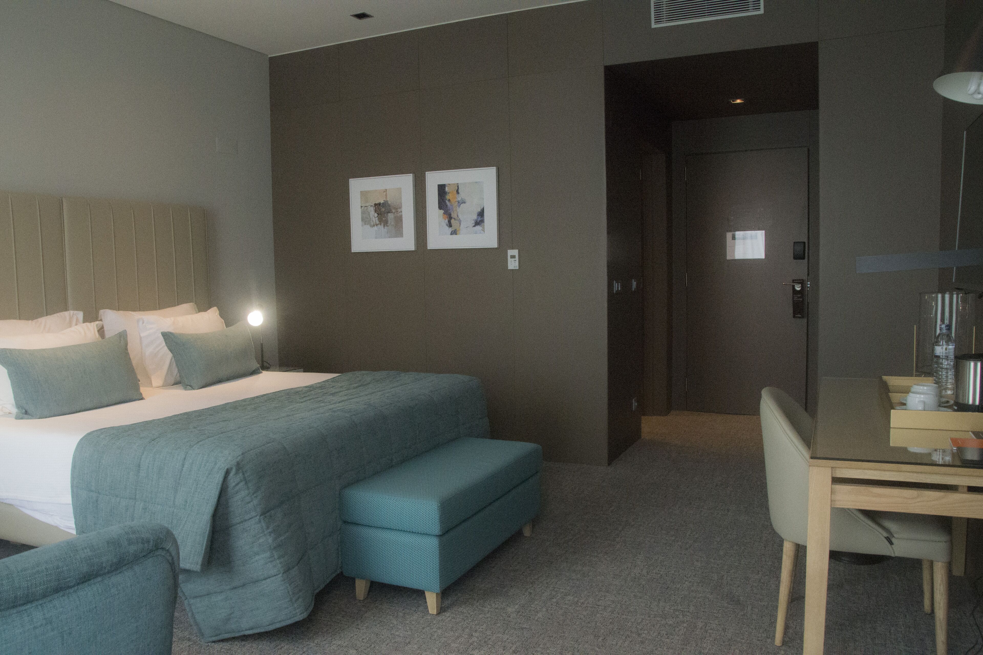 Una habitación de hotel con una cama, un escritorio y dos obras de arte en la pared.