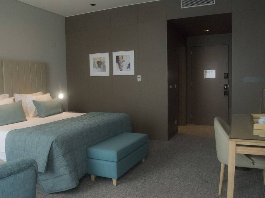 Una habitación de hotel con una cama, un escritorio y dos obras de arte en la pared.