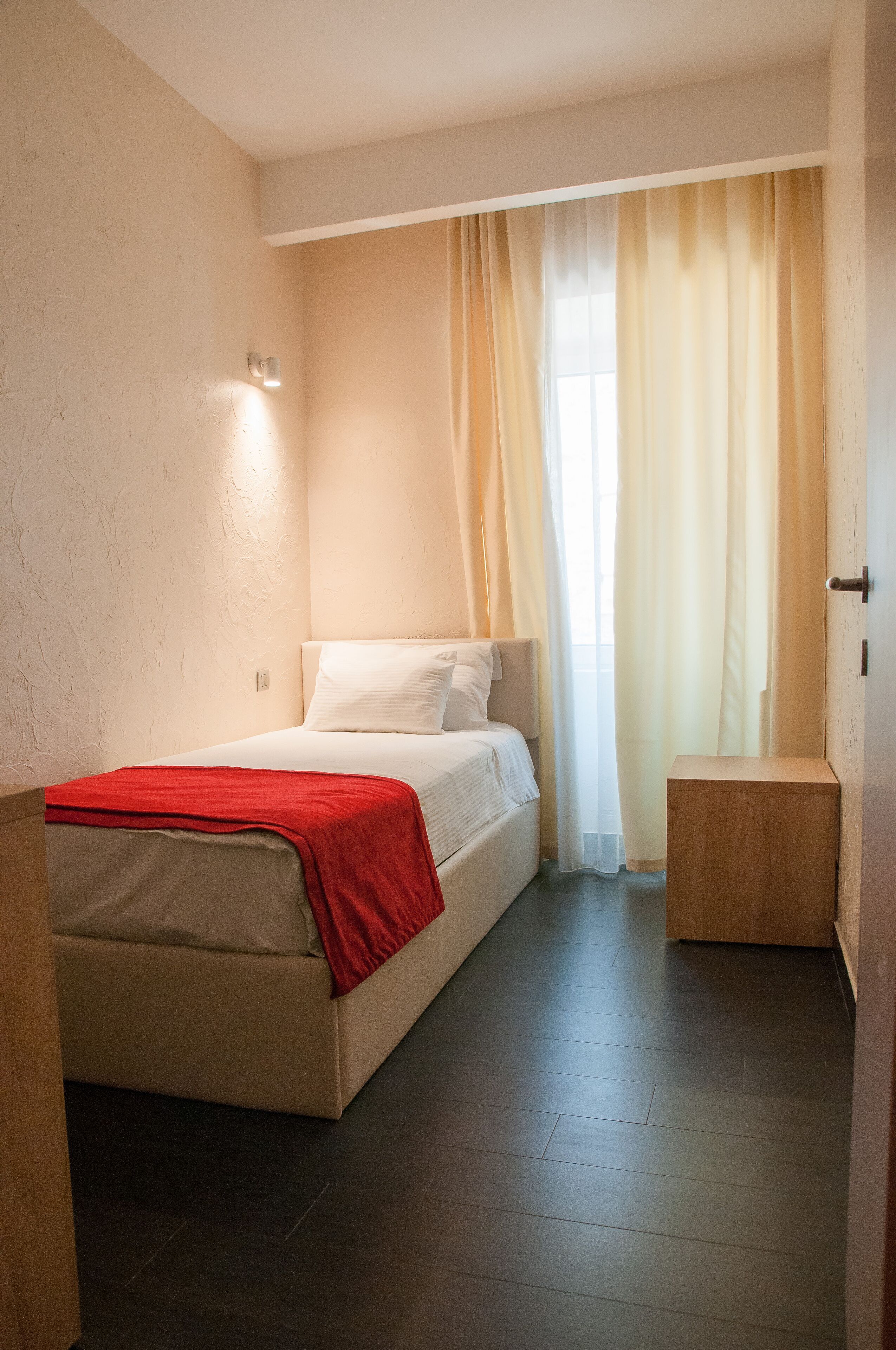 A bedroom with a bed, a bedside table, and a window with curtains.