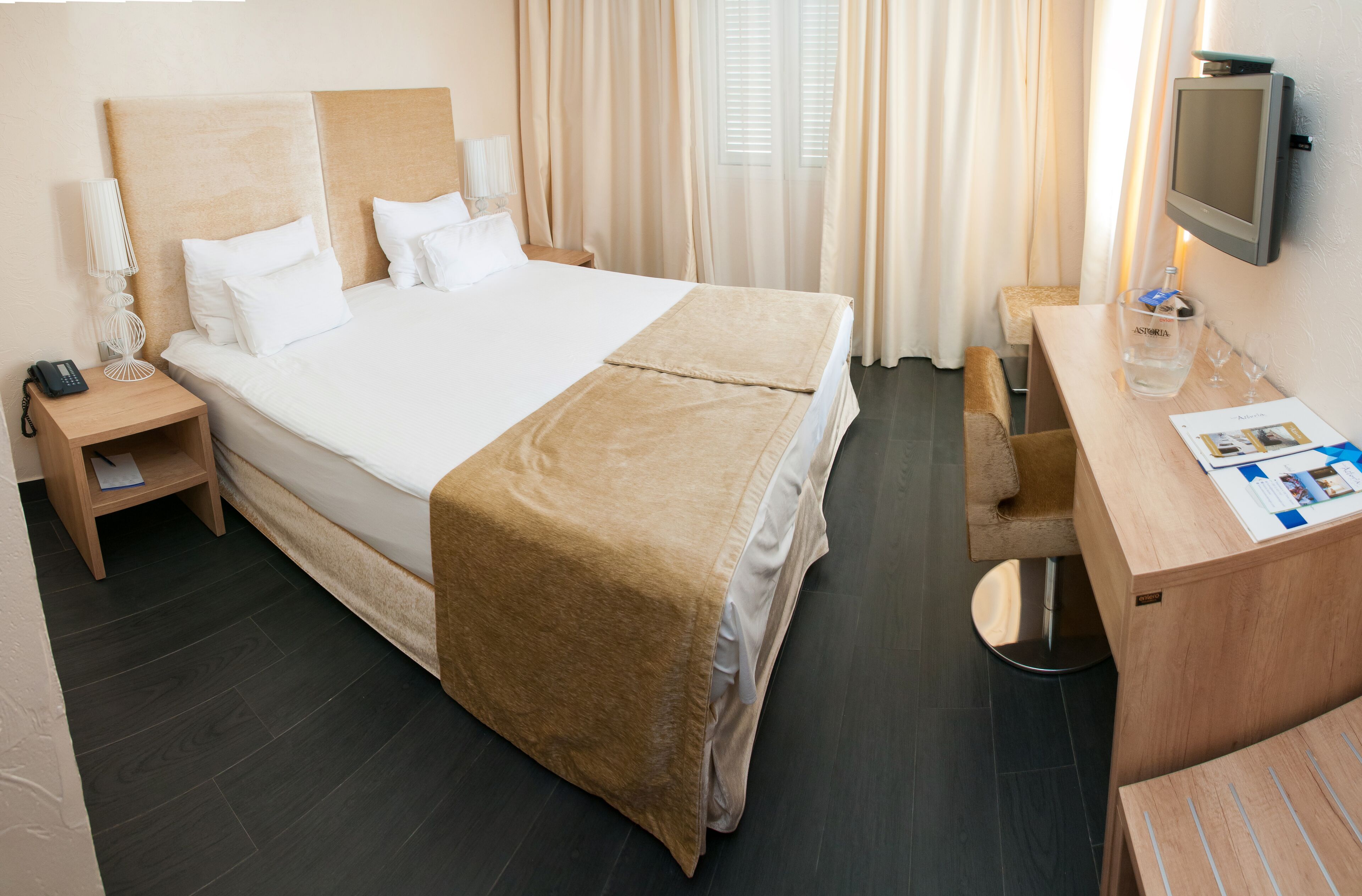 Une chambre d’hôtel avec un grand lit, des tables de chevet, un bureau et une télévision.