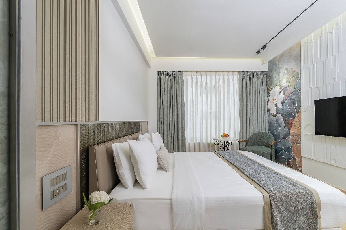 Habitación de hotel con cama, televisión, sillón y decoración en la pared.