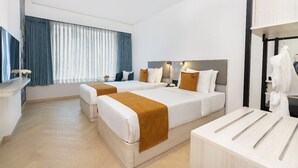 Hotelkamer met twee bedden, een zithoek, een kaptafel met spiegel en een raam met gordijnen.