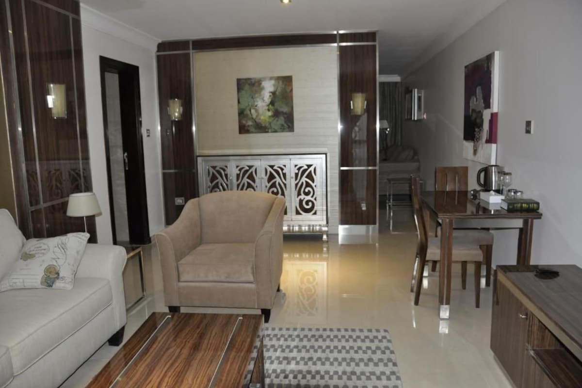 Una sala moderna con sofá, sillón y comedor con mesa y sillas.
